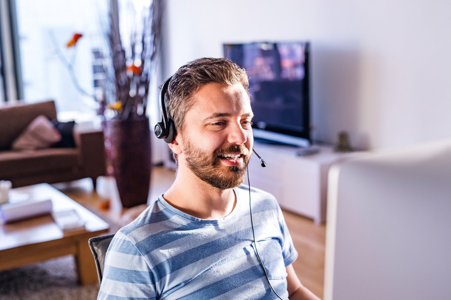 Man Working from Home on Computer, Wearing Headset